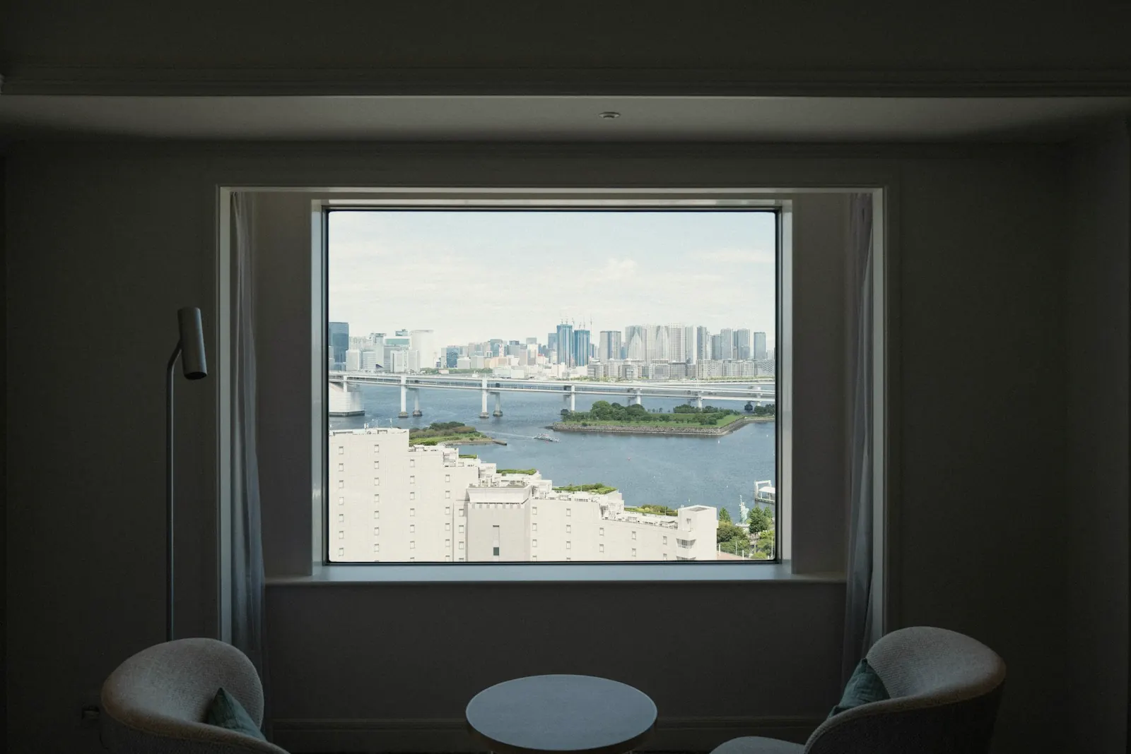 A quiet hotel room with a big window over a city and a bridge