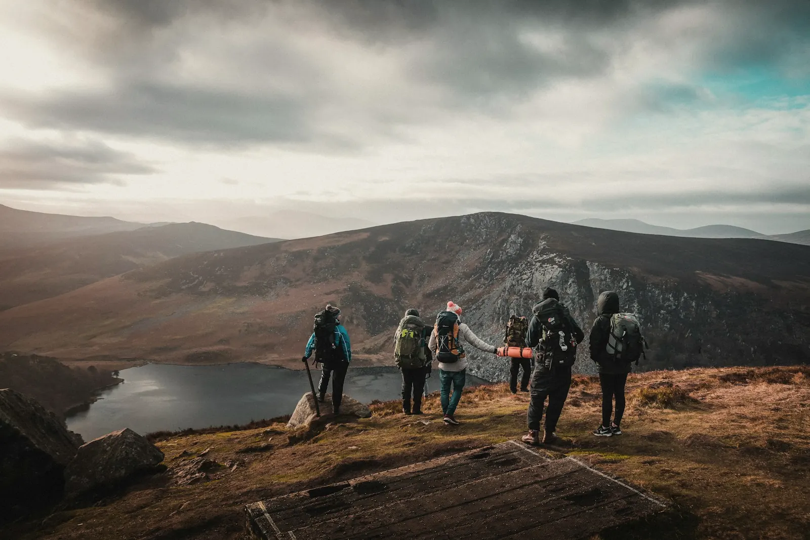 A group of friends walking toward a lake viewpoint in the hills