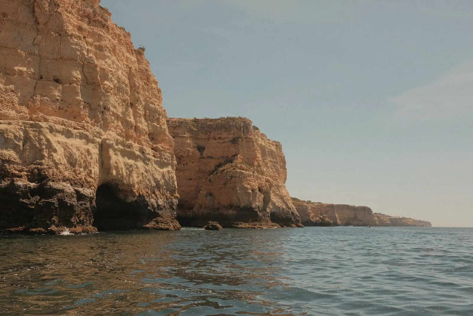 Warm sandstone cliffs dropping into a calm sea